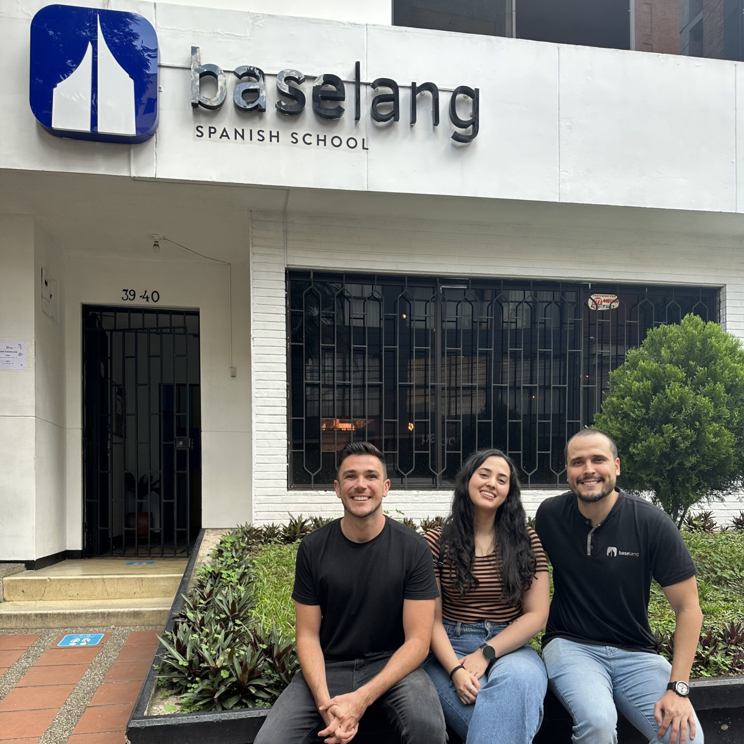 three people sitting in front of Spanish school